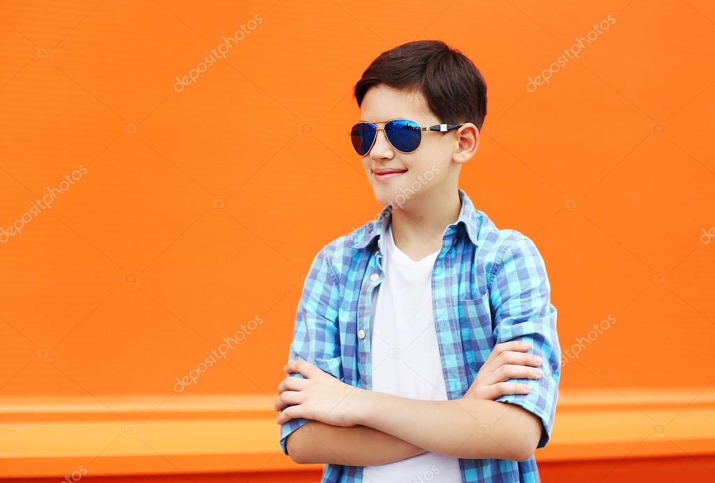 Fashion child boy wearing a sunglasses and shirt in city against