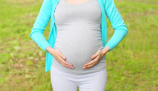 Беременная молодая женщина на открытом воздухе в летний день крупным планом — стоковое фото