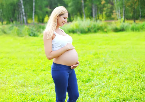 Beautiful young pregnant woman outdoors over summer background, — Zdjęcie stockowe