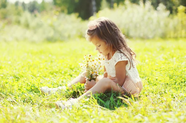 Cute little girl child with bouquet of chamomiles flowers in sum — Stok fotoğraf