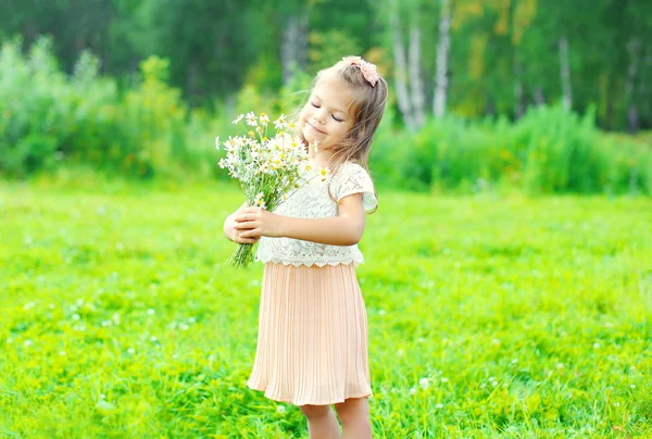 Happy little girl child with bouquet flowers in summer day — Zdjęcie stockowe