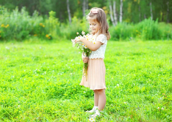 Cute smiling child with bouquet chamomiles flowers in summer day — Stock Fotó
