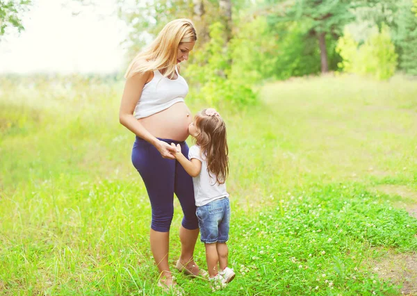 Happy pregnant woman, little child daughter kissing tummy mother — Stok fotoğraf