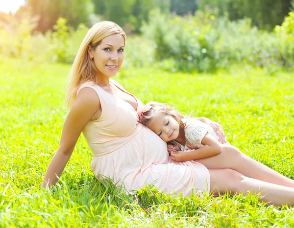 Feliz mujer embarazada, madre sonriente y el niño acostado en la hierba en —  Fotos de Stock