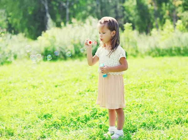 Kleines Mädchen, das an einem Sommertag Seifenblasen pustet — Stockfoto