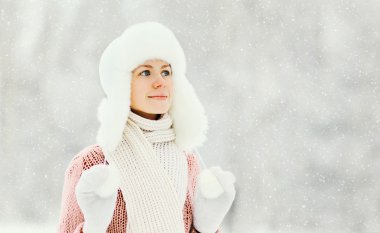 Portrait happy smiling woman wearing a sweater and hat over wint