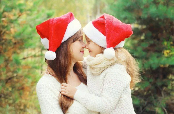 Christmas and family concept - child and mother in santa red hat — Φωτογραφία Αρχείου