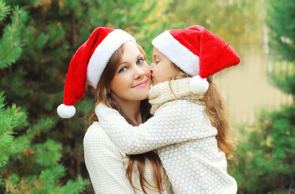 Christmas and family concept - little girl child kissing mother — Stockfoto