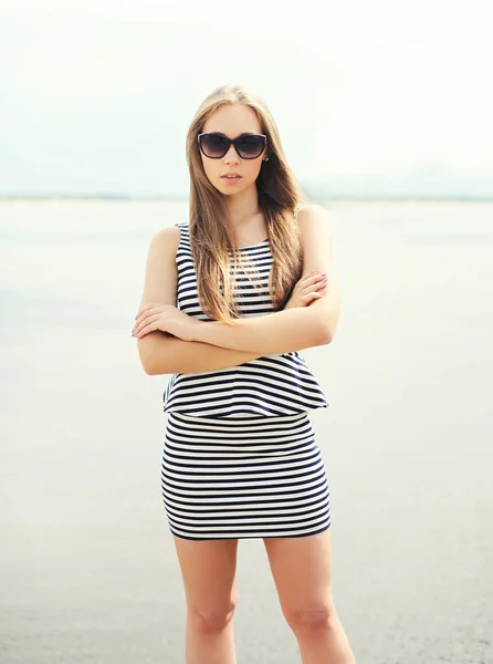 Beautiful young woman wearing a striped dress, sunglasses over s — Stock fotografie