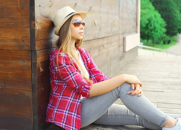 Young woman wearing a pink shirt and summer hat sitting resting — Stock Photo, Image