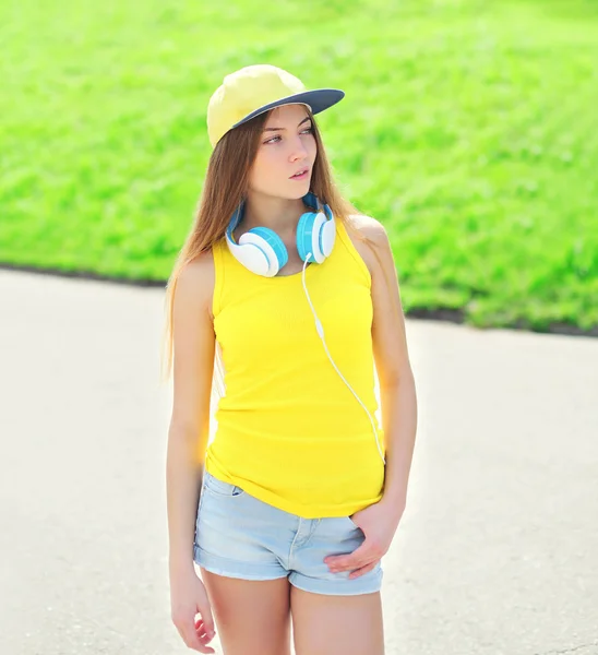 Mode jeune fille portant une casquette, écouteurs et t-shirt en ville — Photo