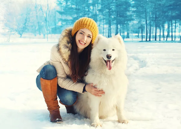 Heureuse femme souriante propriétaire embrassant chien Samoyed blanc en hiver — Photo