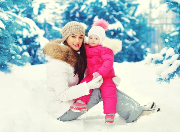 Gelukkig lachend moeder en kind zittend op sneeuw in de winterdag — Stockfoto