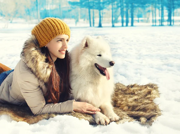 Happy woman owner with white Samoyed dog lying together on snow — Stock Photo, Image