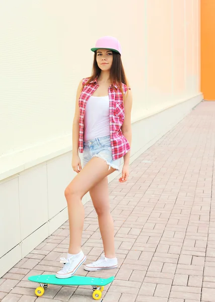 Moda ragazza cool indossa un colorato abiti rosa con skateboar — Foto Stock