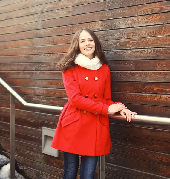 Beautiful young smiling woman wearing a red coat and scarf in ci — Stock Photo, Image