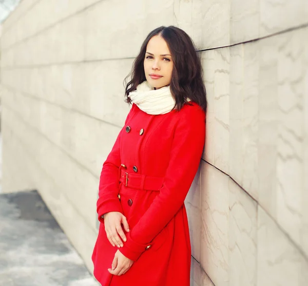 Beautiful young woman wearing a red coat and scarf in the city — Stock Photo, Image