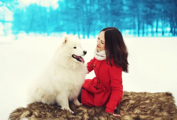 Счастливая молодая женщина владелец с белым самоедом собака на снегу зимой — стоковое фото