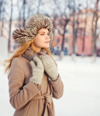 Bir palto ve şapka kışın kar üzerinde giyen güzel genç kadın