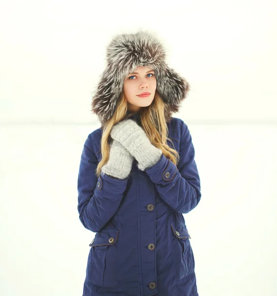 Belle femme portant une veste et un chapeau sur la neige en hiver — Photo