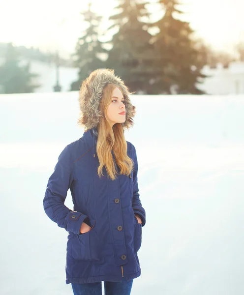 Beautiful blonde woman wearing a coat jacket with hood over snow — Stock Photo, Image