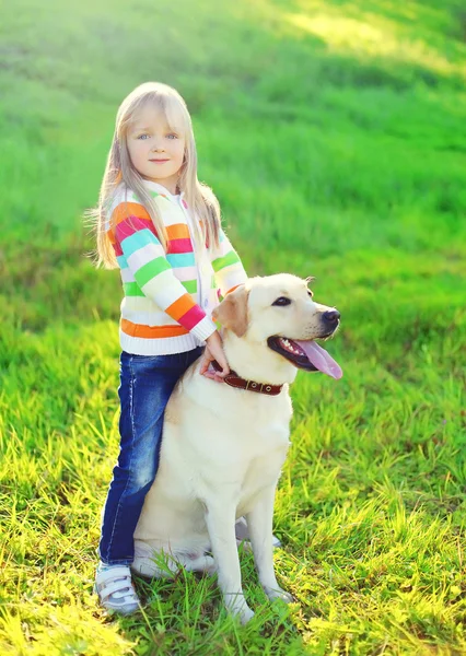Kind geht im Sommer mit Labrador-Retriever-Hund auf Gras spazieren — Stockfoto