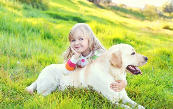 Enfant heureux et chien labrador retriever couché sur l'herbe en été — Photo