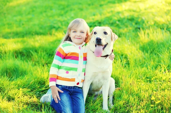 Onnellinen lapsi leikkii labrador noutaja koira ruohoa summ — kuvapankkivalokuva