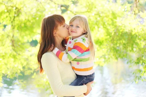 Happy mother kissing daughter child in summer day — Stock Photo, Image