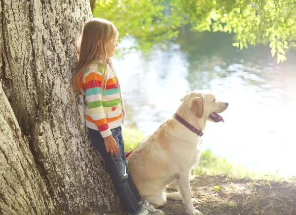 Petit enfant avec Labrador retriever chien dans le parc d'été près de wat — Photo