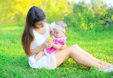 Şirin anne ve bebek güneşli summ çimlere oturup çiçekli
