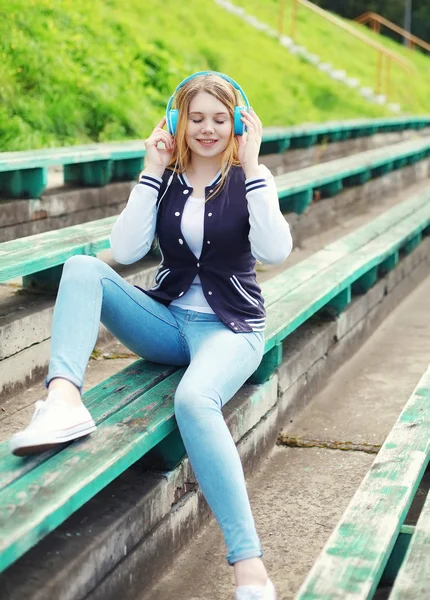 Gelukkig jong meisje met koptelefoon vergadering naar muziek in cit luistert — Stockfoto