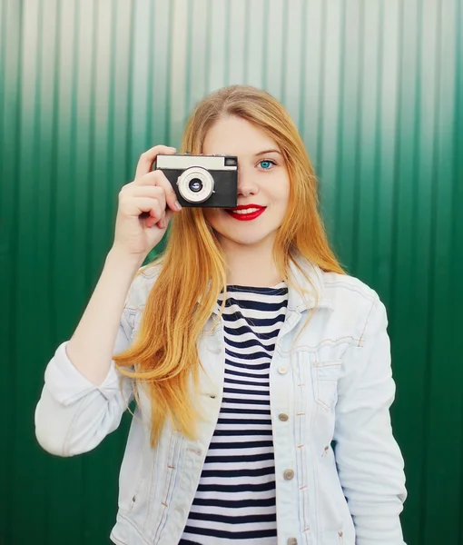 Pretty young girl with retro vintage camera in city over green b — Stock Photo, Image