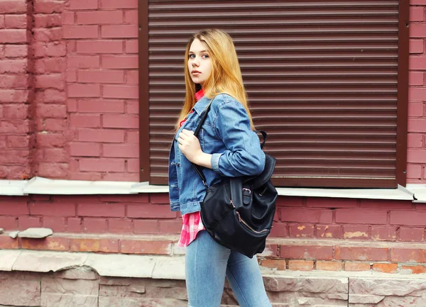 Chica joven con una chaqueta vaqueros y bolso negro caminando en la ciudad — Foto de Stock