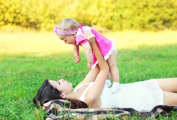 Šťastná matka a dítě spolu leží na trávě baví v summ — Stock fotografie