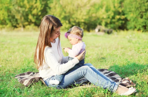 Glückliche Mutter und Baby sitzen zusammen im Gras an einem sonnigen Tag — Stockfoto