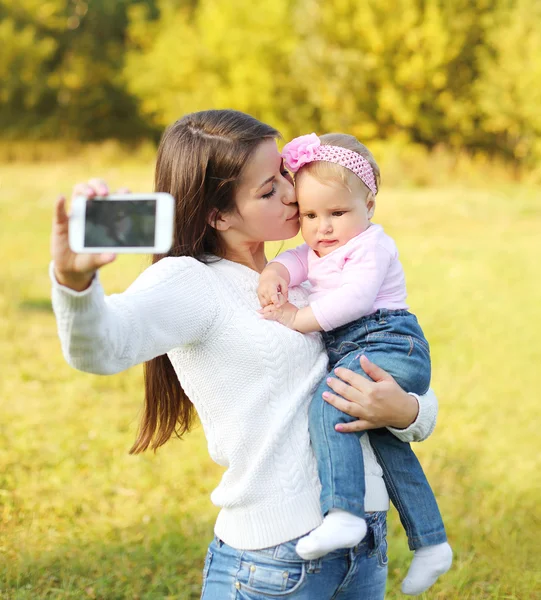 Glückliche Mutter und Baby beim Selbstporträt auf dem Smartphone in der Sonne — Stockfoto
