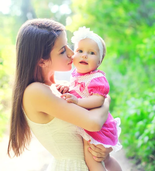 Mãe feliz abraçando e beijando bebê no dia de verão — Fotografia de Stock