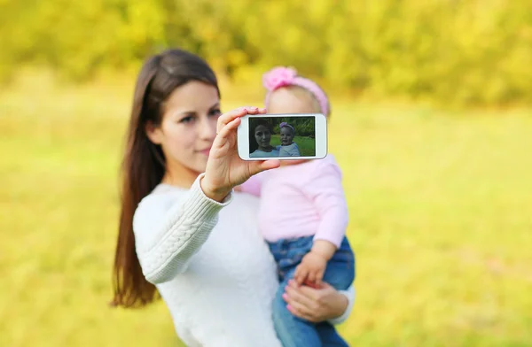Мать и ребенок делают автопортрет на смартфоне в солнечном сумме — стоковое фото