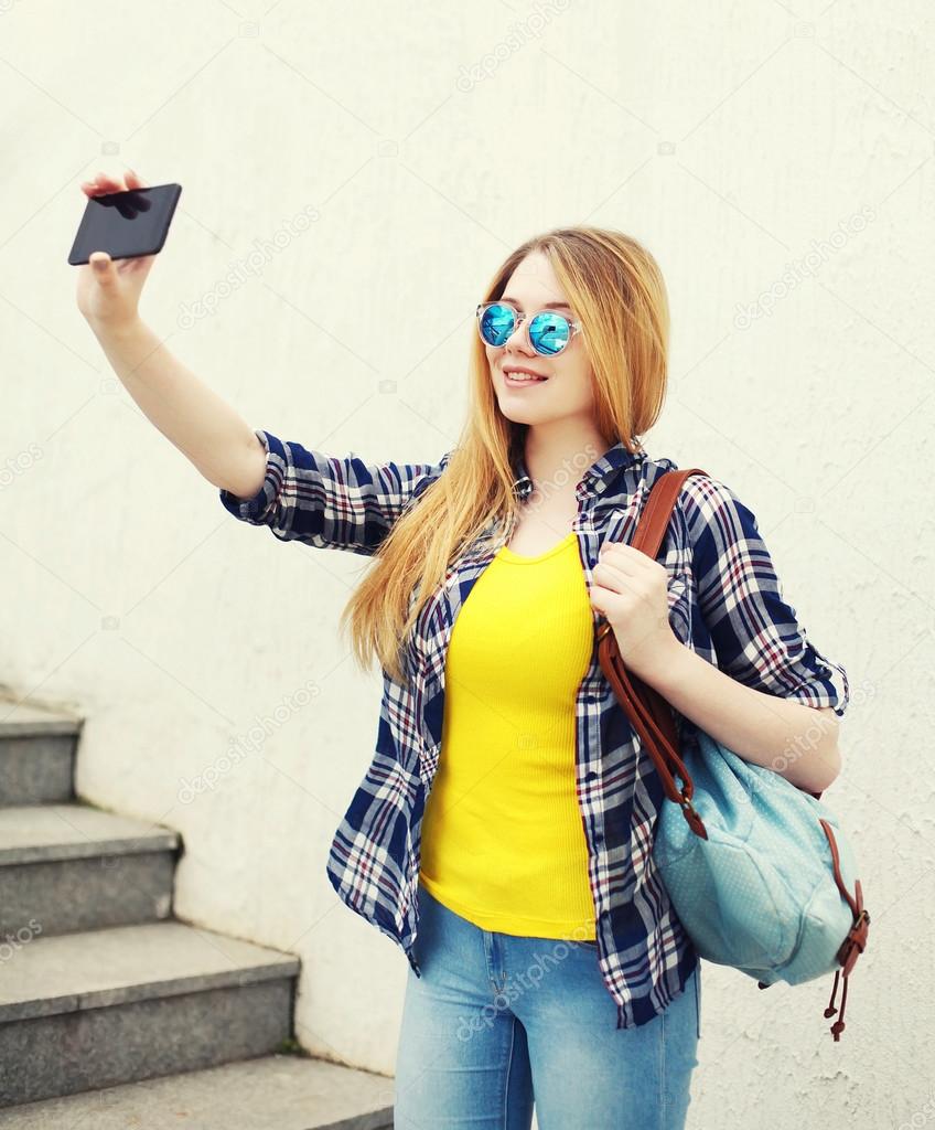 Fashion pretty young girl makes selfie portrait on smartphone in