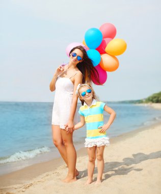 Mutlu anne ve çocuk renkli balonlar beach n üzerinde yürüme ile