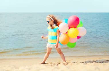Yaz plaj renkli balonlarla oynarken küçük kız çocuğu