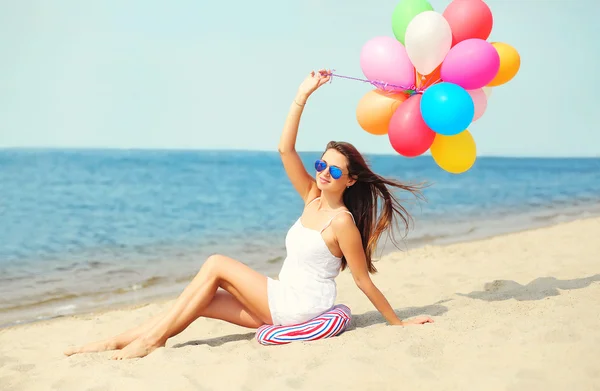 Joyeux sourire jeune femme avec des ballons colorés sur la plage près de s — Photo