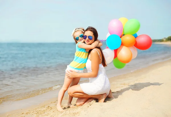 Madre e hijo abrazándose con globos de colores en la playa cerca de se —  Fotos de Stock