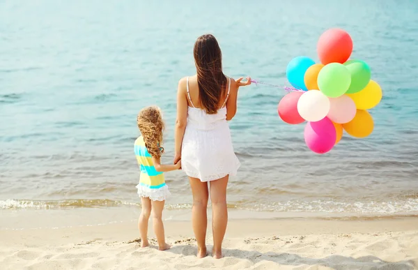 Madre e hijo con globos de colores de pie en la playa cerca de s —  Fotos de Stock