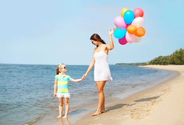 Madre e hijo con globos de colores caminando en la playa cerca de se —  Fotos de Stock