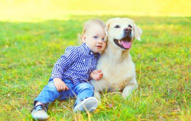 Küçük çocuk çocuk ile Golden Retriever köpek çimlerin üzerine oturan