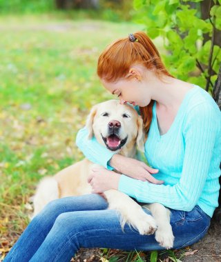 Mutlu sahibi kadın kucaklama Golden Retriever köpek çimlerin üzerine