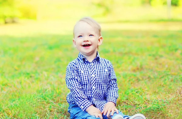 Šťastný usměvavý chlapec dítě sedět na trávě v slunečný den — Stock fotografie