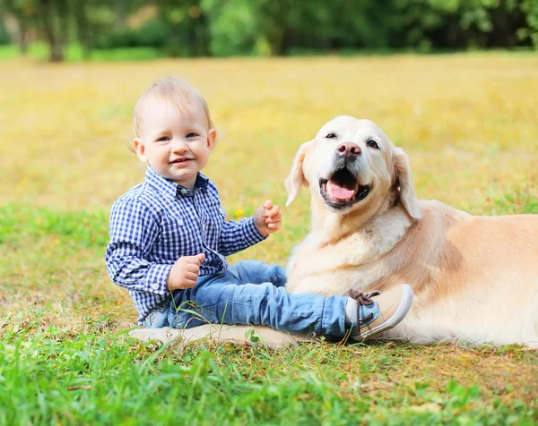 Feliz menino sorridente criança e Golden Retriever cão sentado — Fotografia de Stock